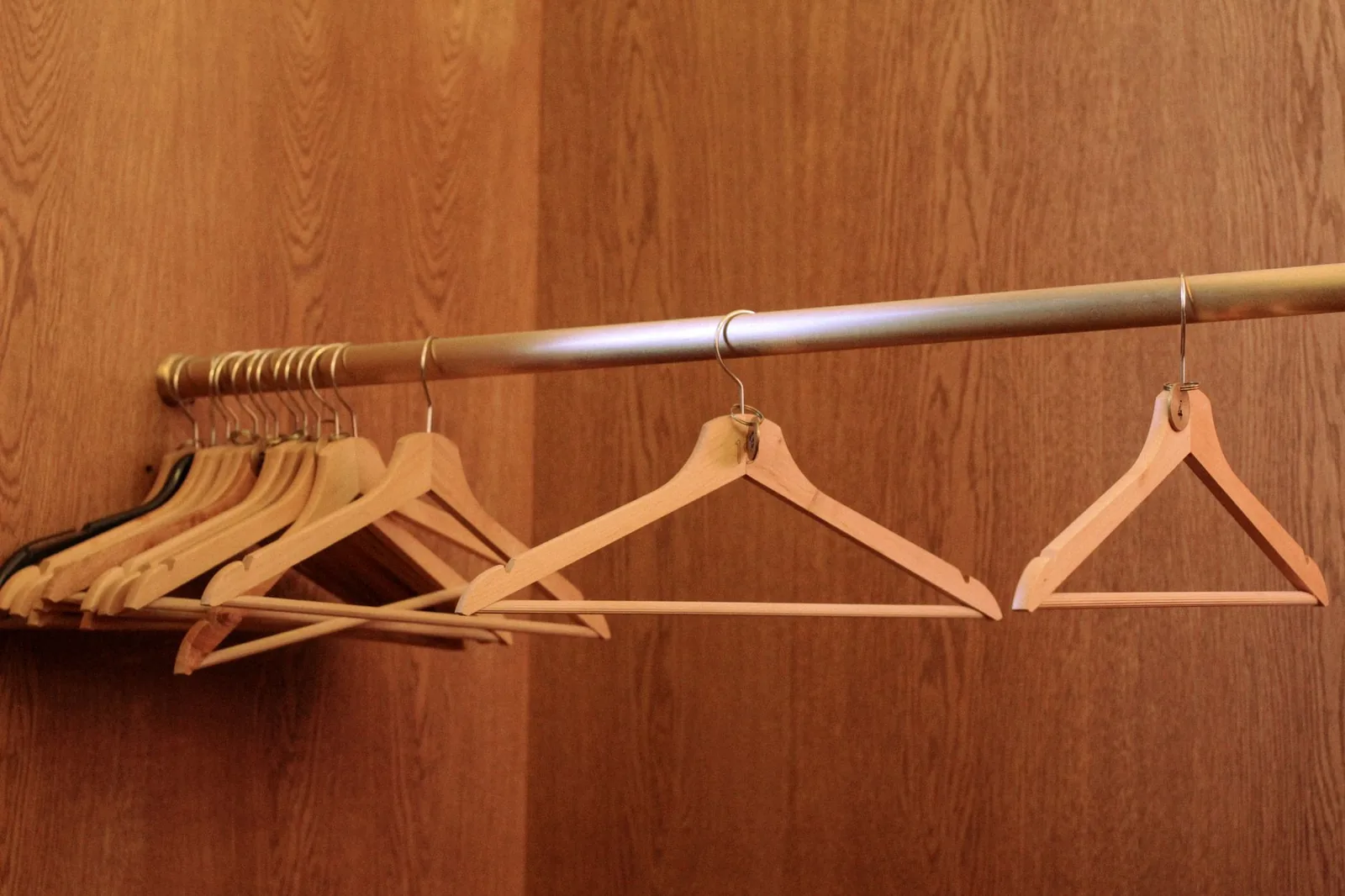 Wooden hangers on a metal rail in an empty wood-panelled closet